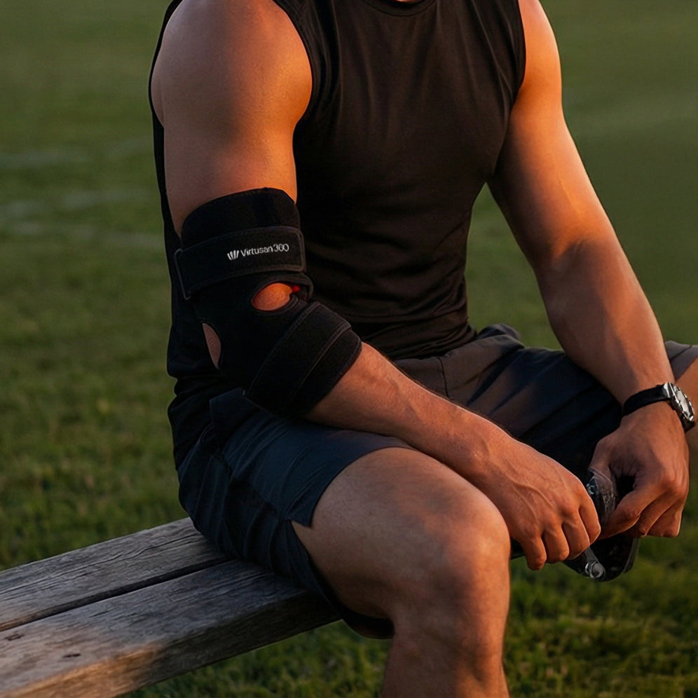 Person sitting on a wooden bench outdoors with a black red light therapy joiny strap support on an arm.