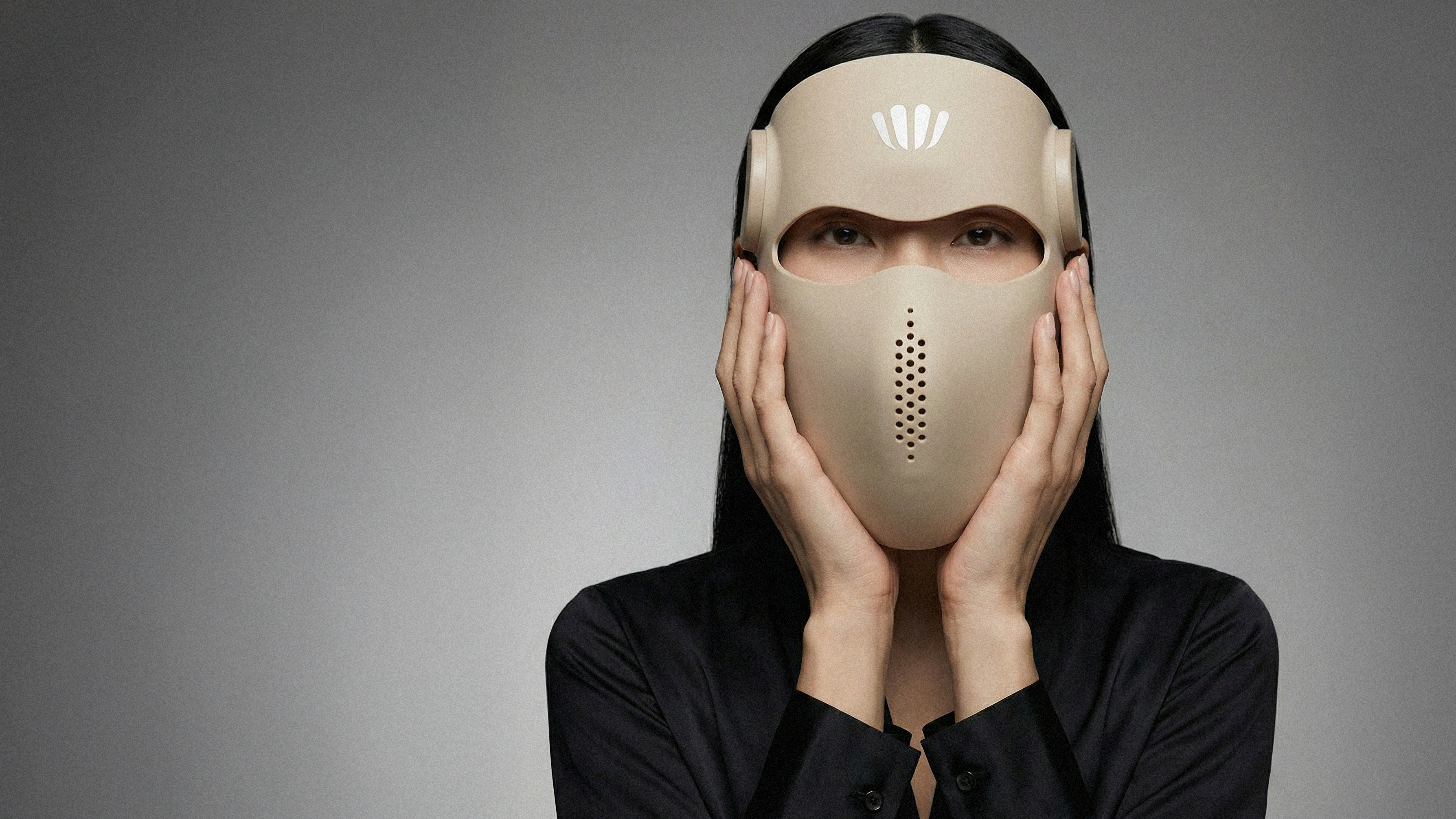 Person wearing a red light therapy facemask with a logo on a gray background