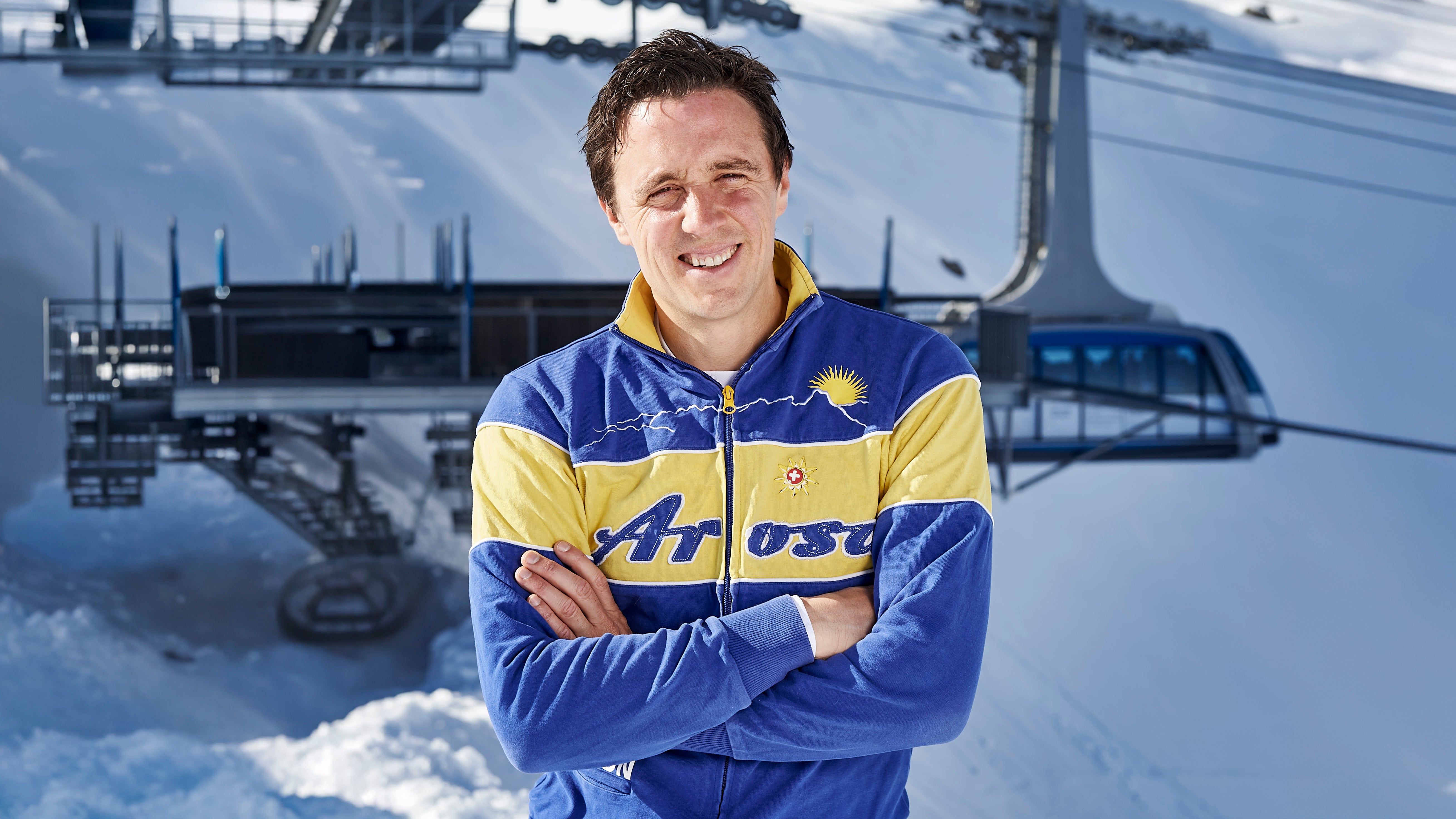 Pascal Jenny wearing a blue and yellow jacket with 'trosa' branding in a snowy landscape.
