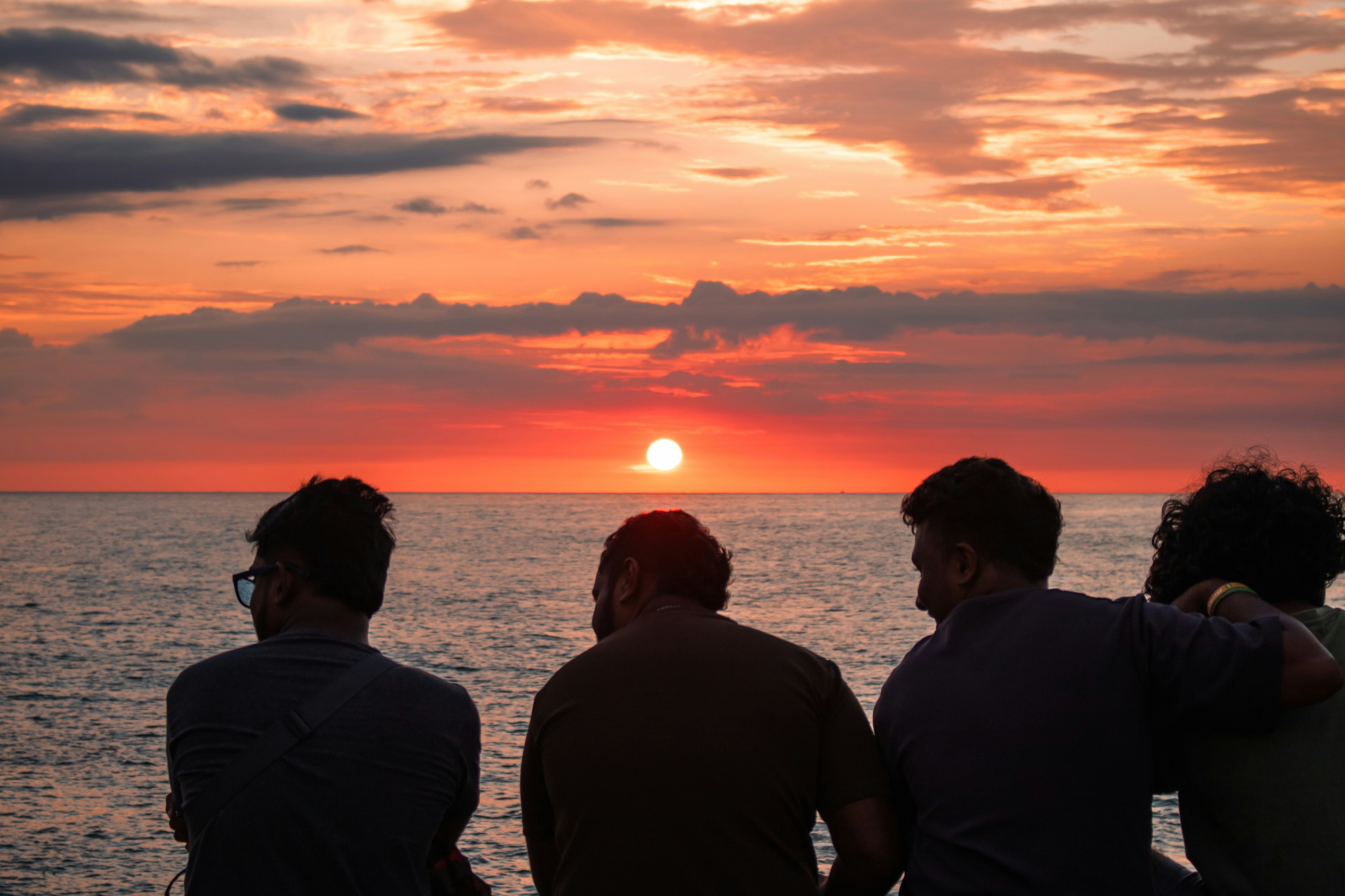 Four people watching a sunset over water
