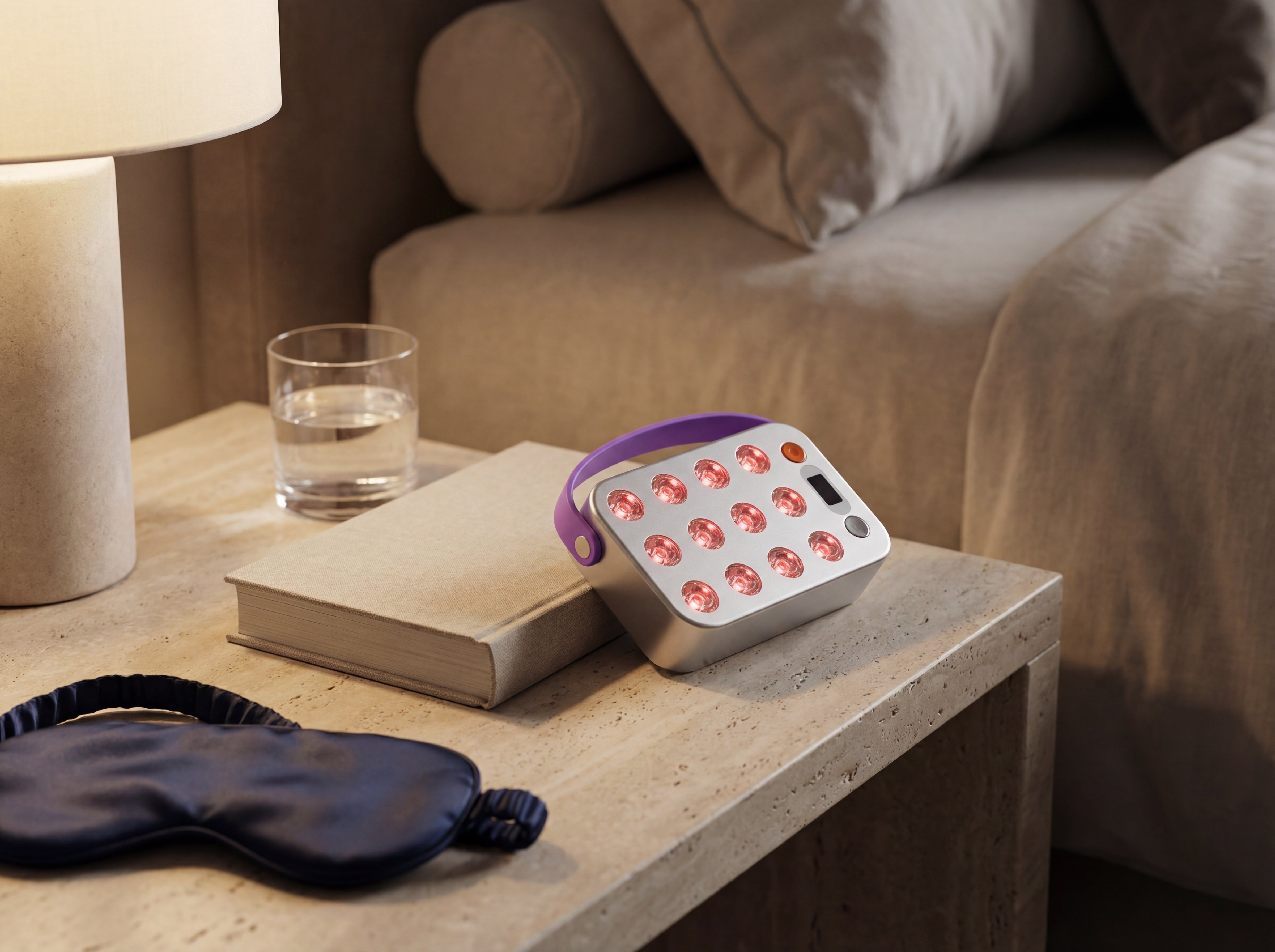 White and purple red light therapy device on a nightstand with a book, glass of water, and eye mask in a house in Switzerland.